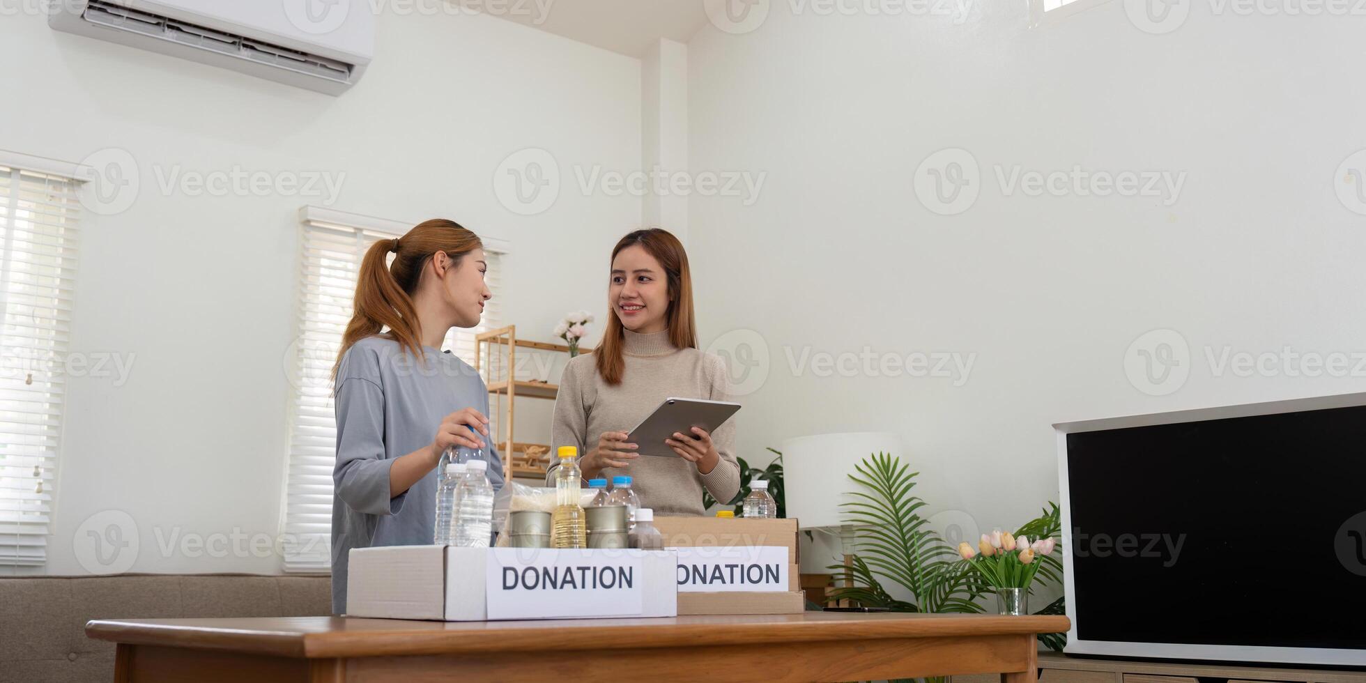 Happy young woman volunteer collecting, sorting food for needy people, team working together on donation project in charitable at home photo