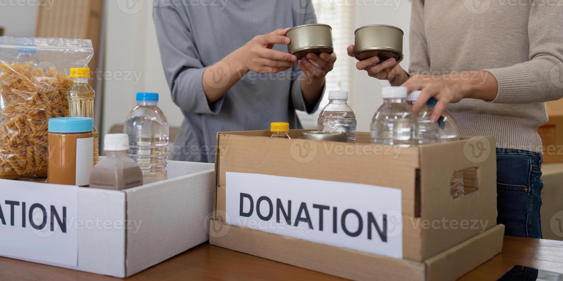 Group of volunteer woman working in home. Happy volunteer looking at food donation box separating donations stuffs photo