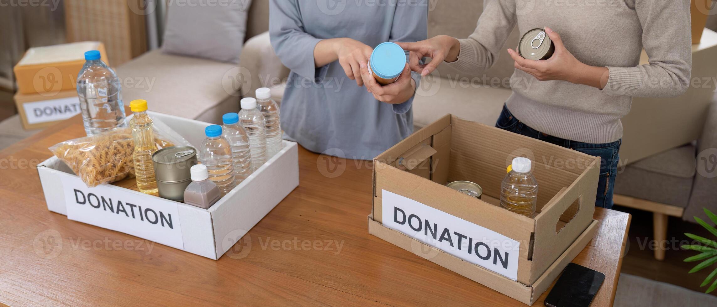 Group of volunteer woman working in home. Happy volunteer looking at food donation box separating donations stuffs photo