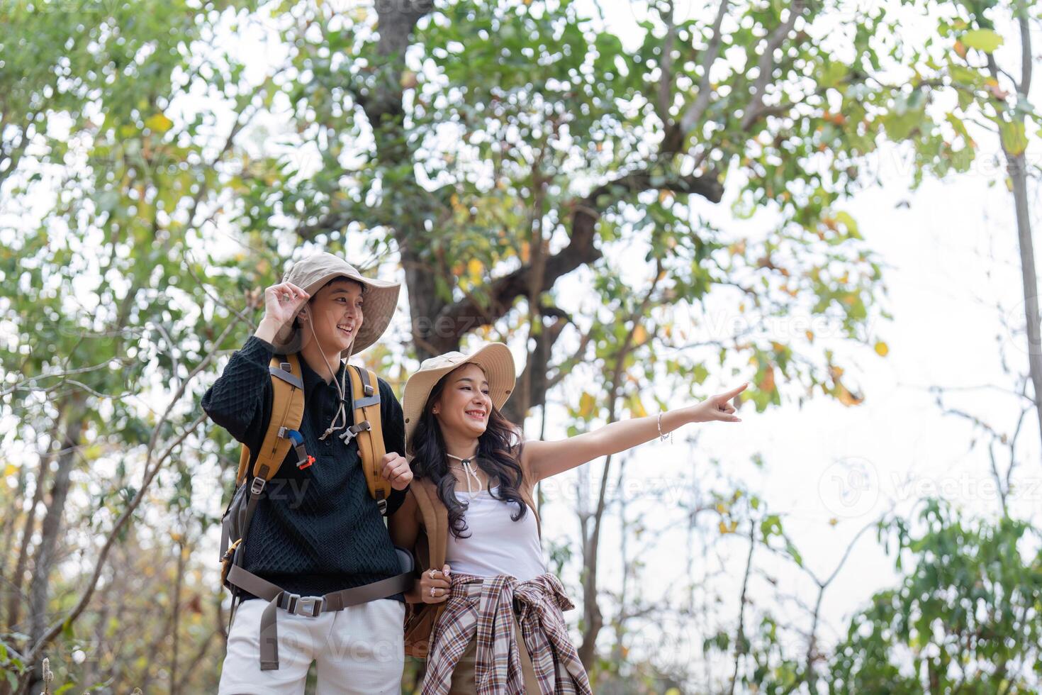 Cheerful romantic lesbian couple traveler with backpack on their backs go hiking through the forest in the mountains in summer photo