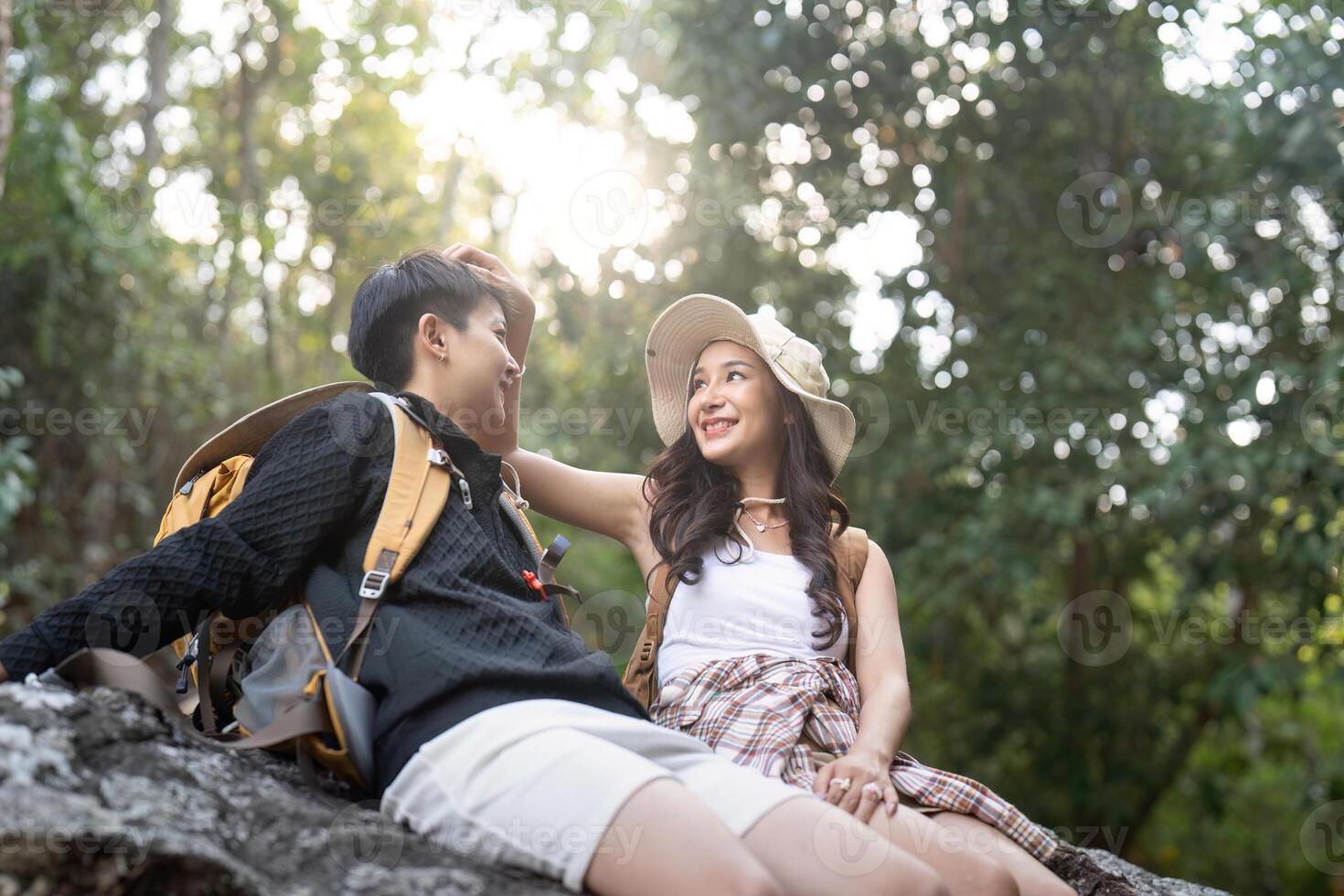 Lovely couple lesbian woman with backpack relaxing while hiking in nature. Loving LGBT romantic moment in mountains photo