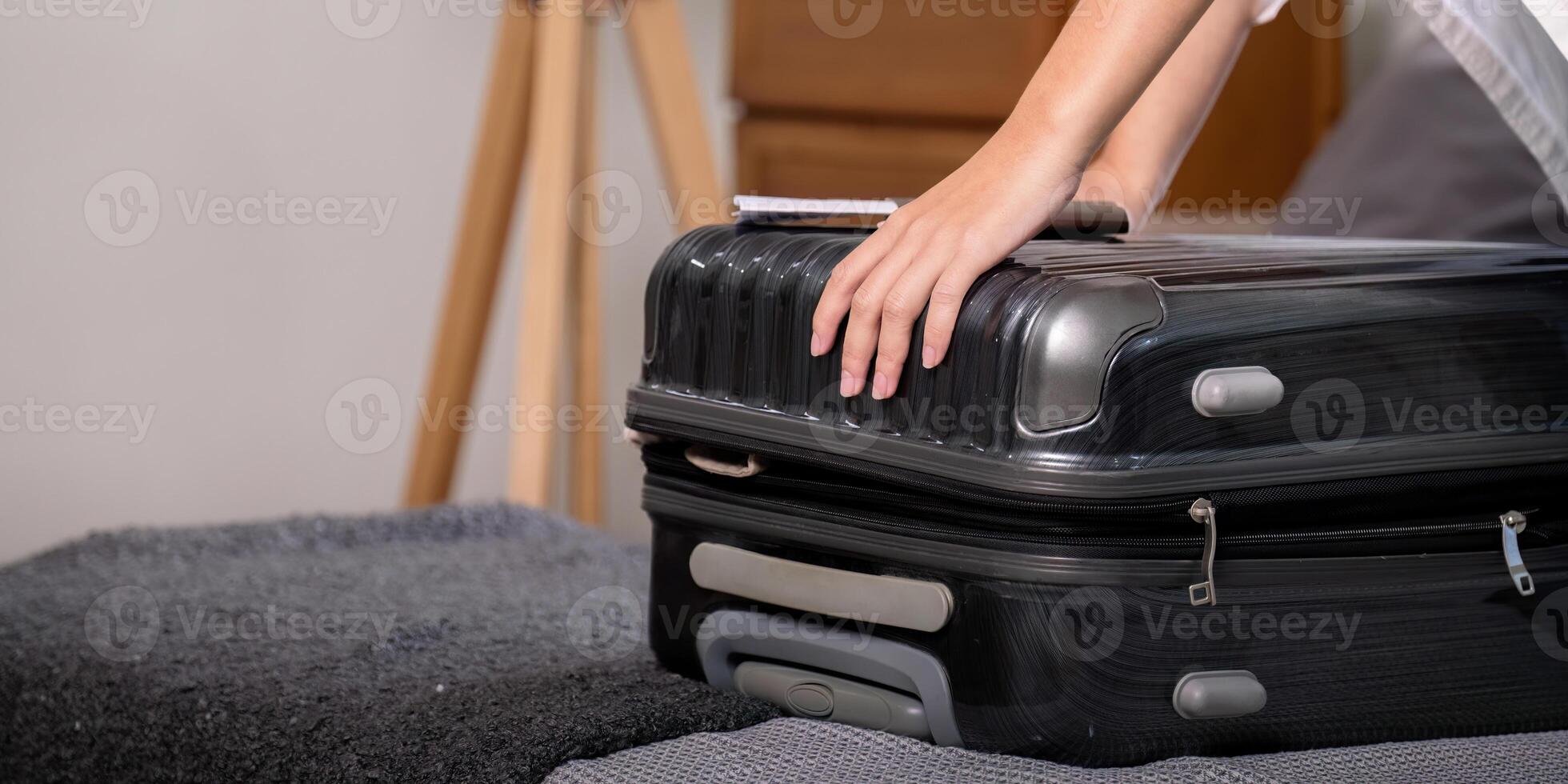 Young woman asian traveler sitting on the sofa packing her suitcase preparing for travel on summer vacation photo