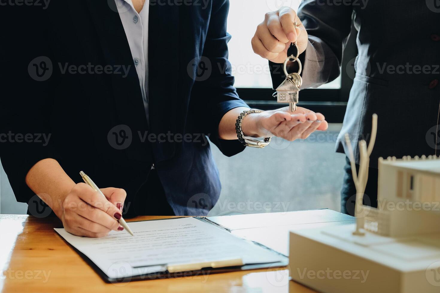 estate agent giving house keys to woman and sign agreement in office photo
