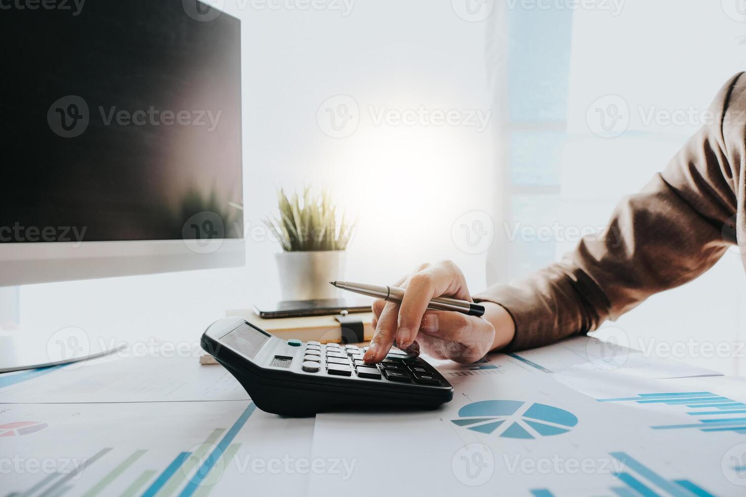Close up of Business woman or accountant using calculator during analysis on data paper photo