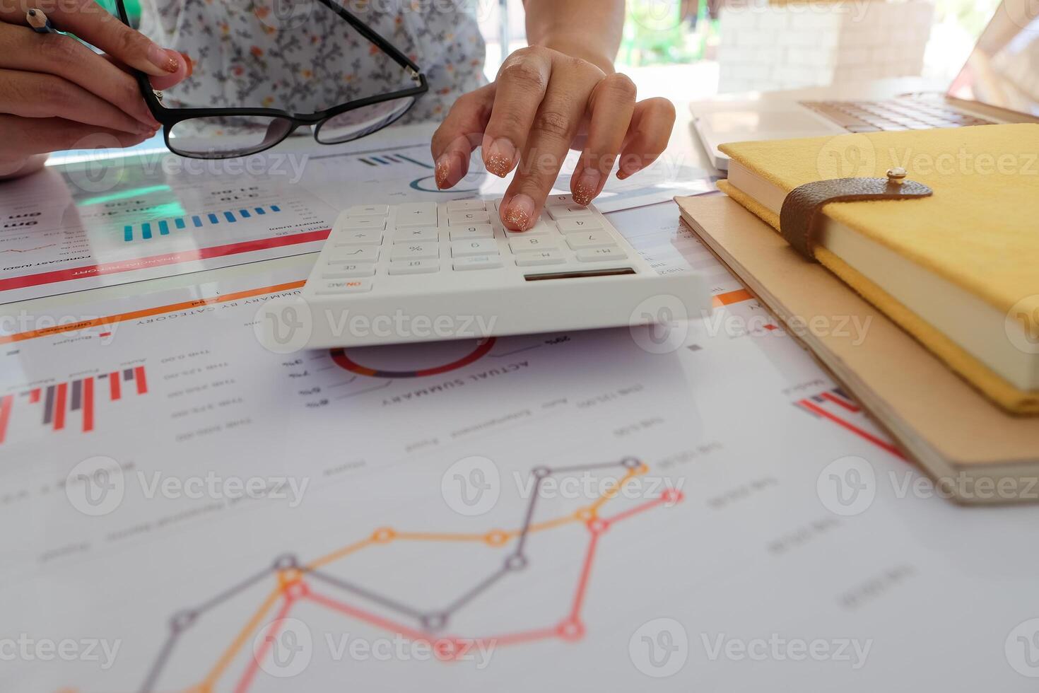 Close up of businessman or accountant hand holding pencil working on calculator to calculate financial data report, photo