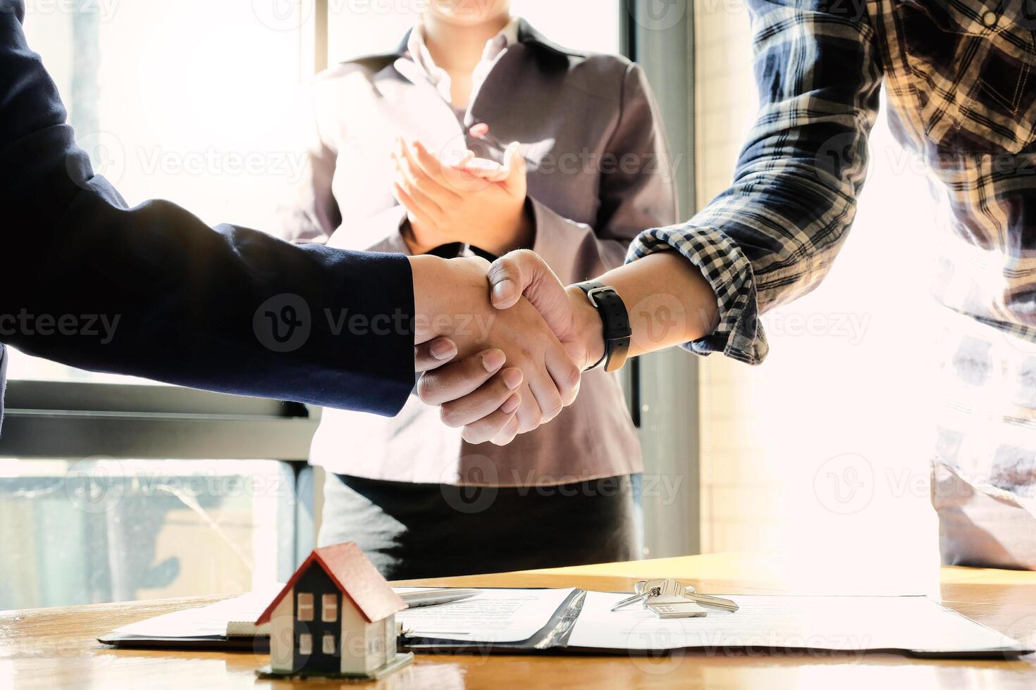 Real estate agent and customers shaking hands together celebrating finished contract after about home insurance photo