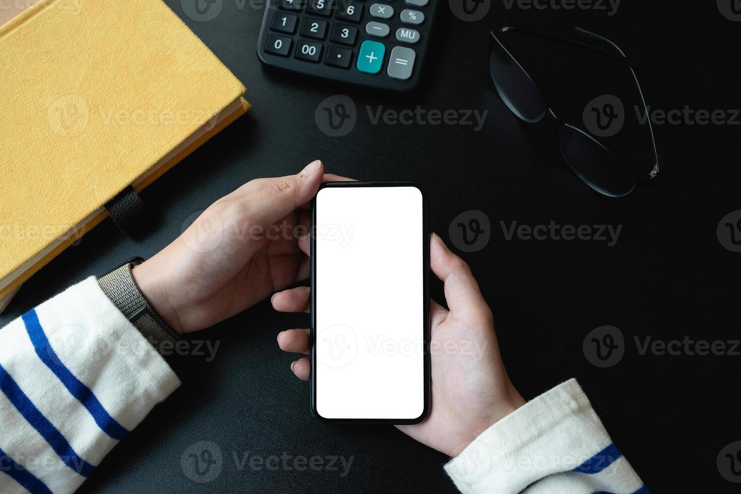 Top view of woman holding blank screen smartphone in dark trendy workspace photo