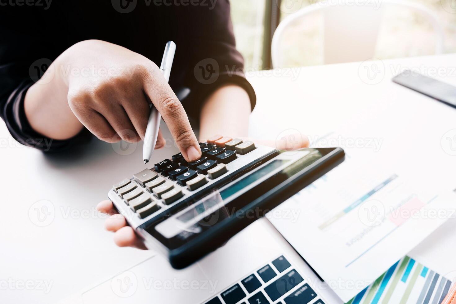 Close up Business woman using calculator for do math finance on wooden desk photo