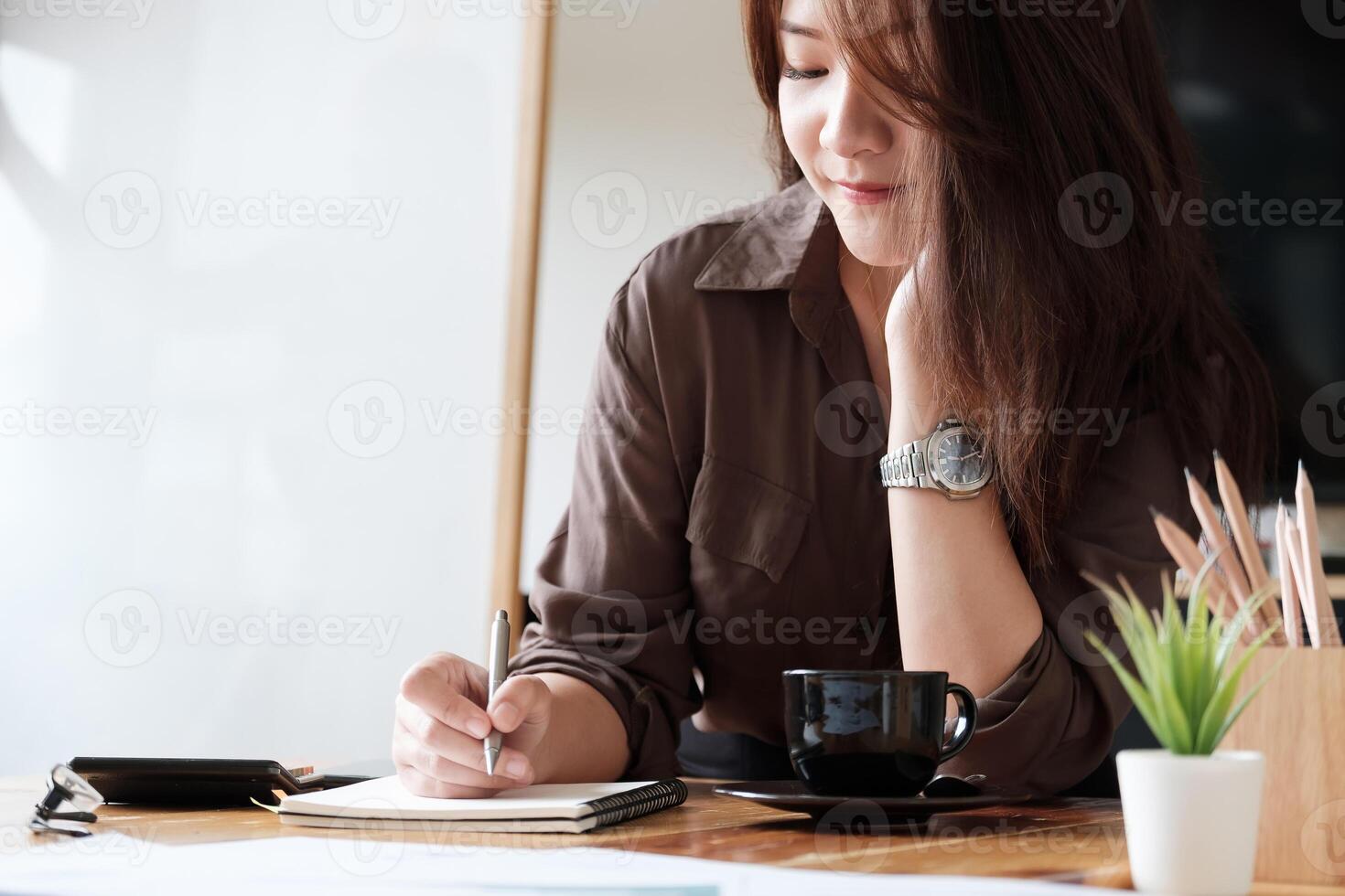 Attractive accountant counting on calculator, making notes some data on notepad photo