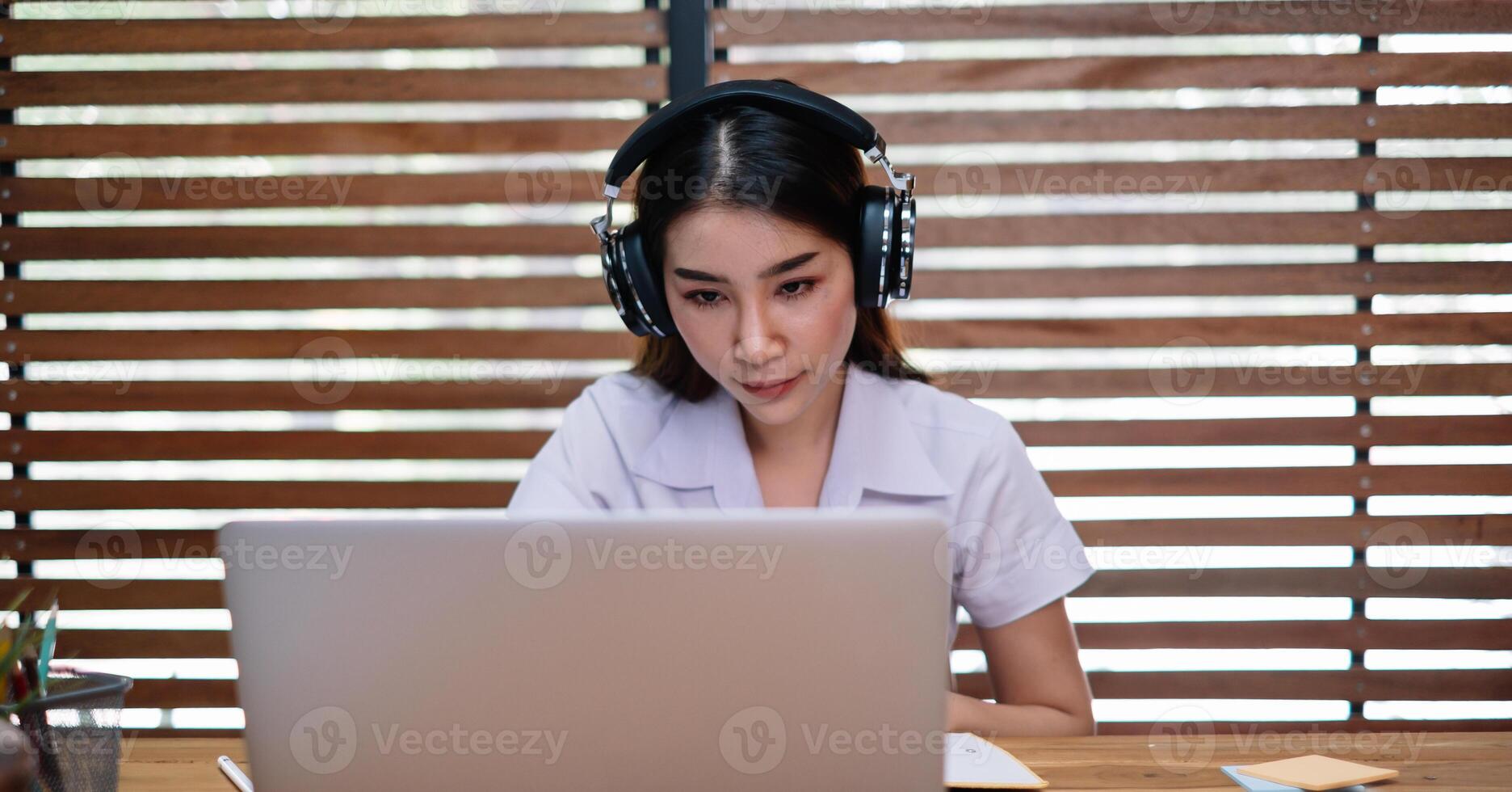 Young beautiful female using laptop computer for studying or entrepreneur working with a laptop and notes at home photo