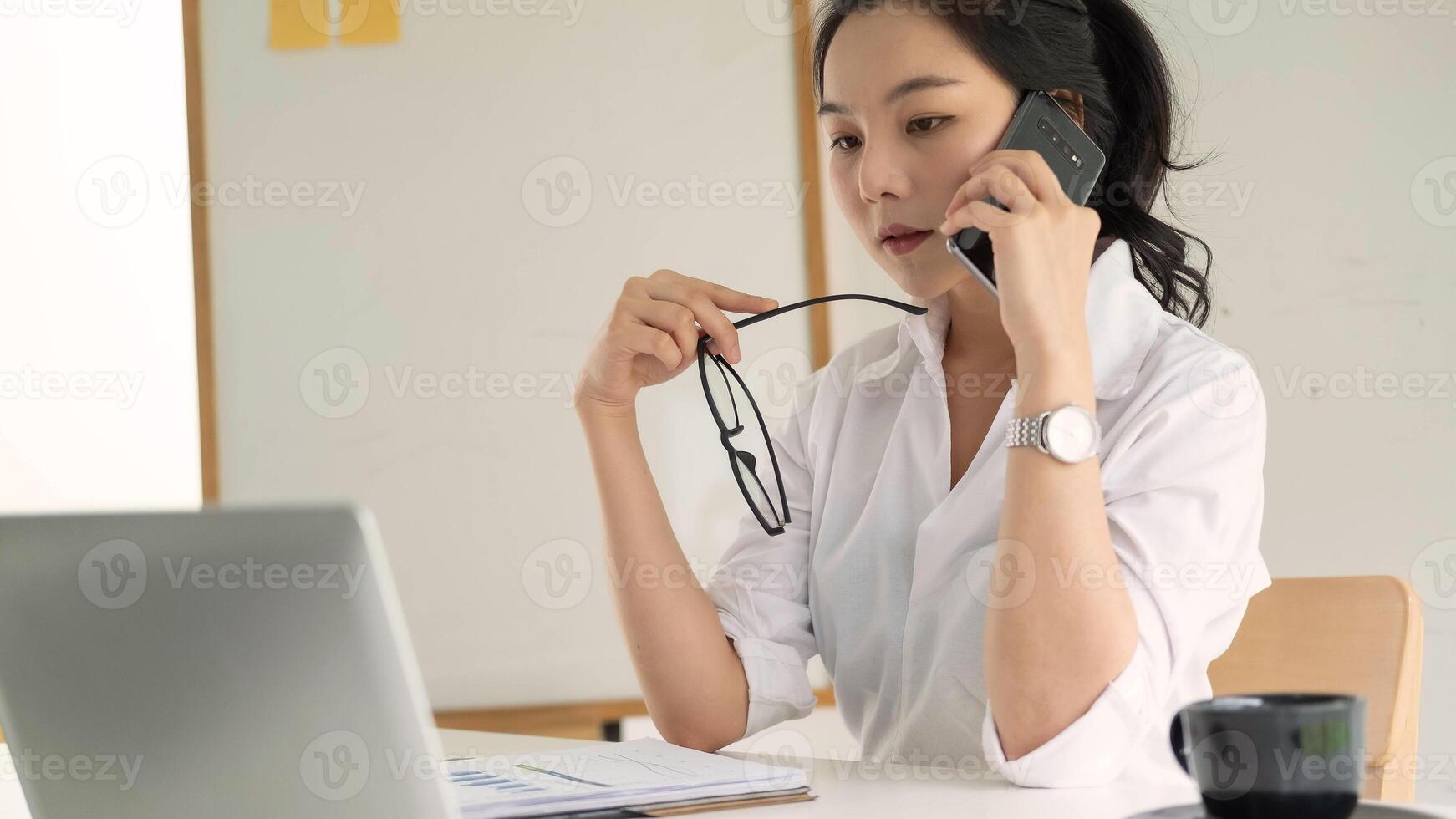 Young female entrepreneur working laptop computer and talking mobile phone photo