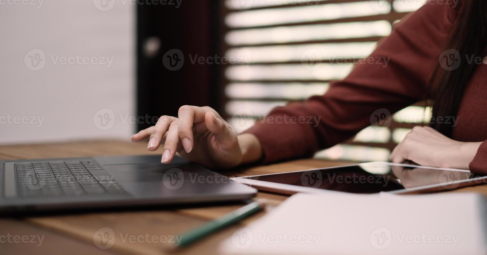 Close up of woman hands using on laptop computer for online learning on wooden table at home photo