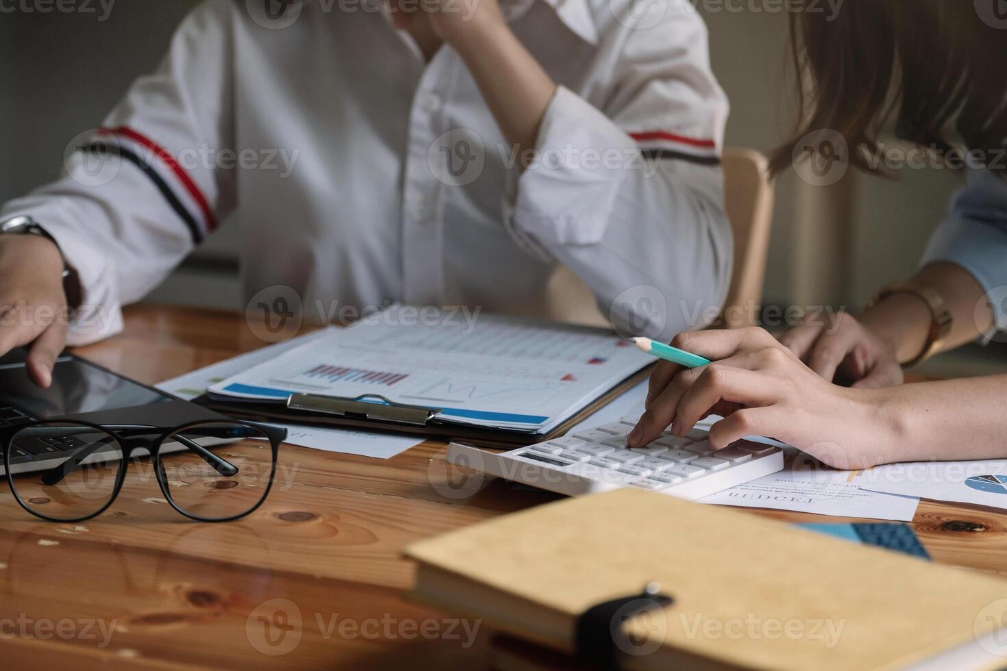 Business team using a calculator and laptop computer to calculate the numbers in office photo