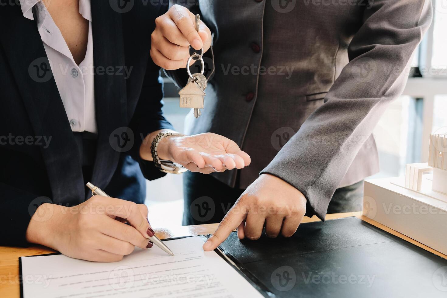 estate agent giving house keys to man and sign agreement in office photo