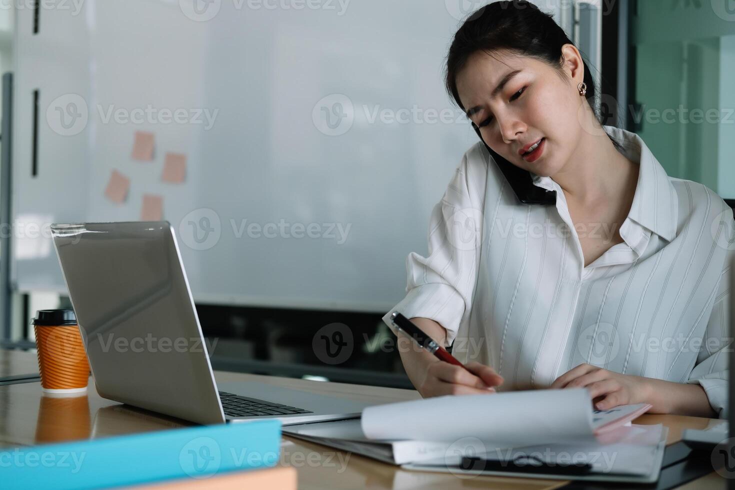 Young accountant hand holding smartphone to call marketing consultants and using laptop computer to analyze sales growth in the global workplace market. accounting concept. photo