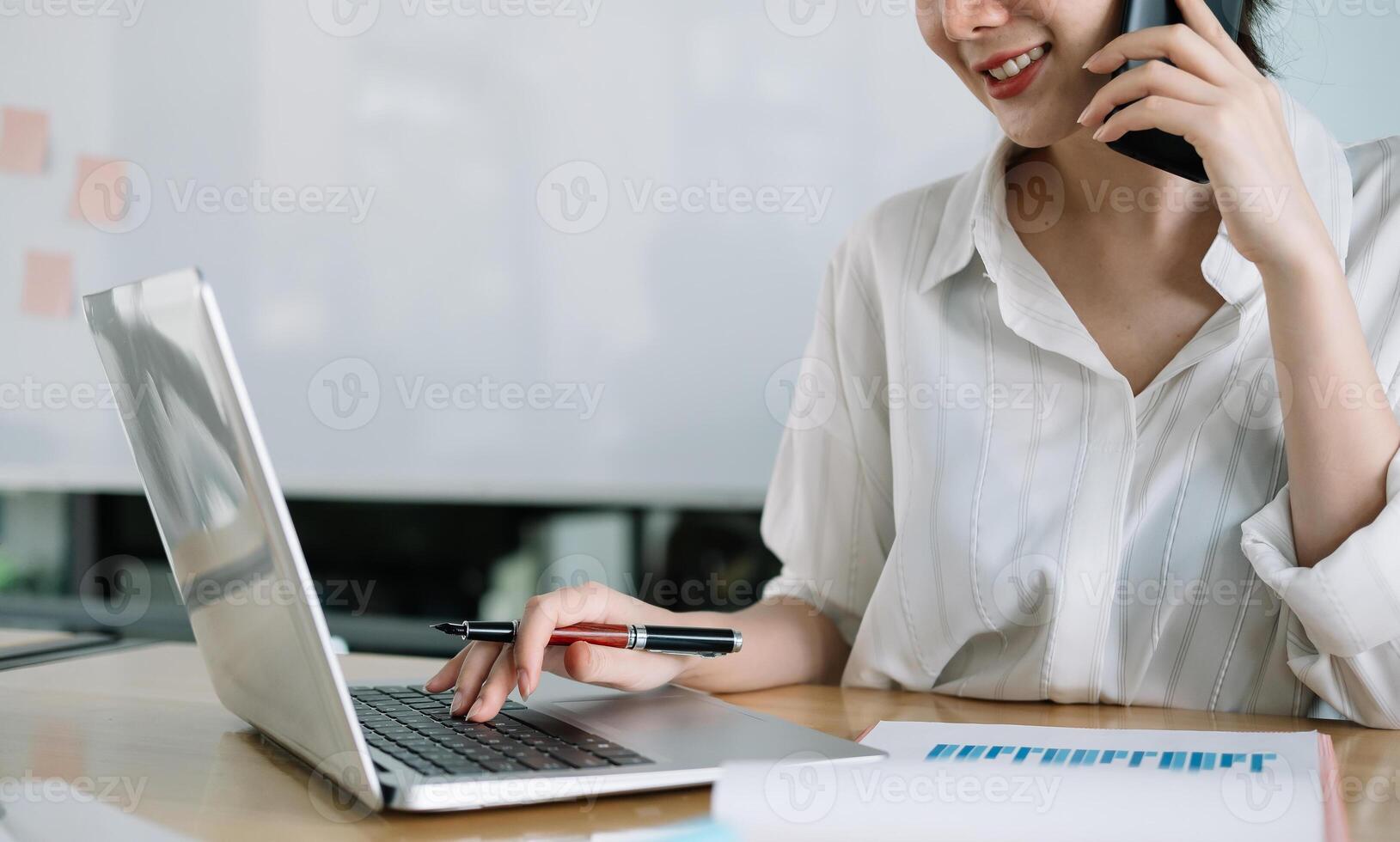 Young accountant hand holding smartphone to call marketing consultants and using laptop computer to analyze sales growth in the global workplace market. accounting concept photo