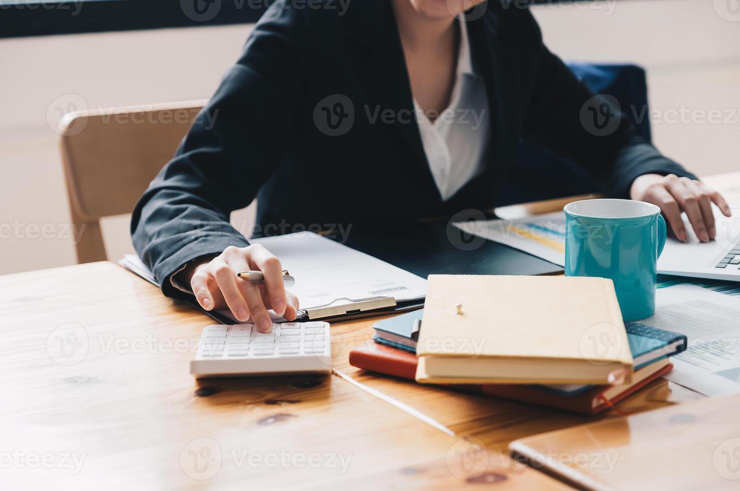 Close up of businesswoman or accountant hand holding pencil working on calculator to calculate financial data report, accountancy document and laptop computer at office, business concept photo