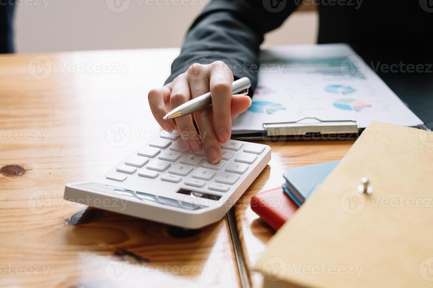 Close up of businesswoman or accountant hand holding pencil working on calculator to calculate financial data report, accountancy document and laptop computer at office, business concept photo