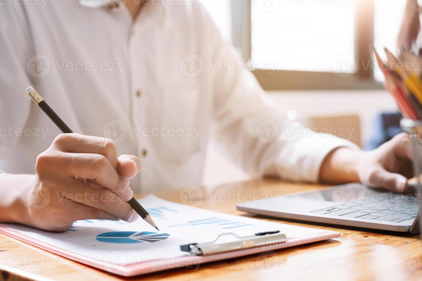 Businessman pen pointing turnover with graph chart report and use laptop computer for analysis data photo