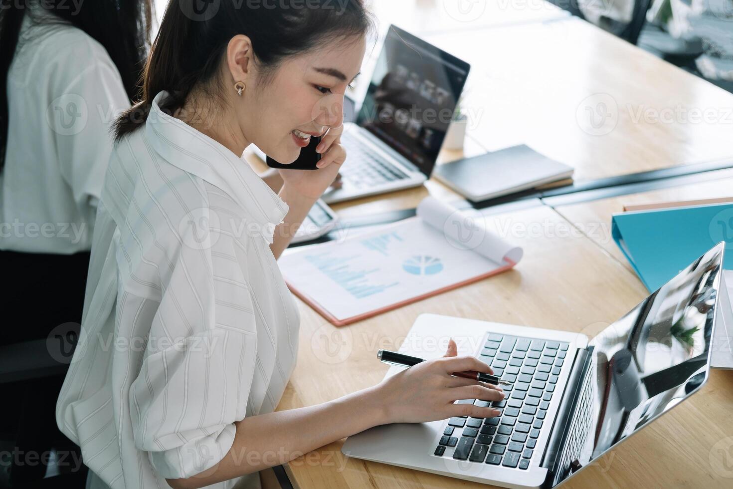 Young accountant hand holding smartphone to call marketing consultants and using laptop computer to analyze sales growth in the global workplace market. accounting concept photo