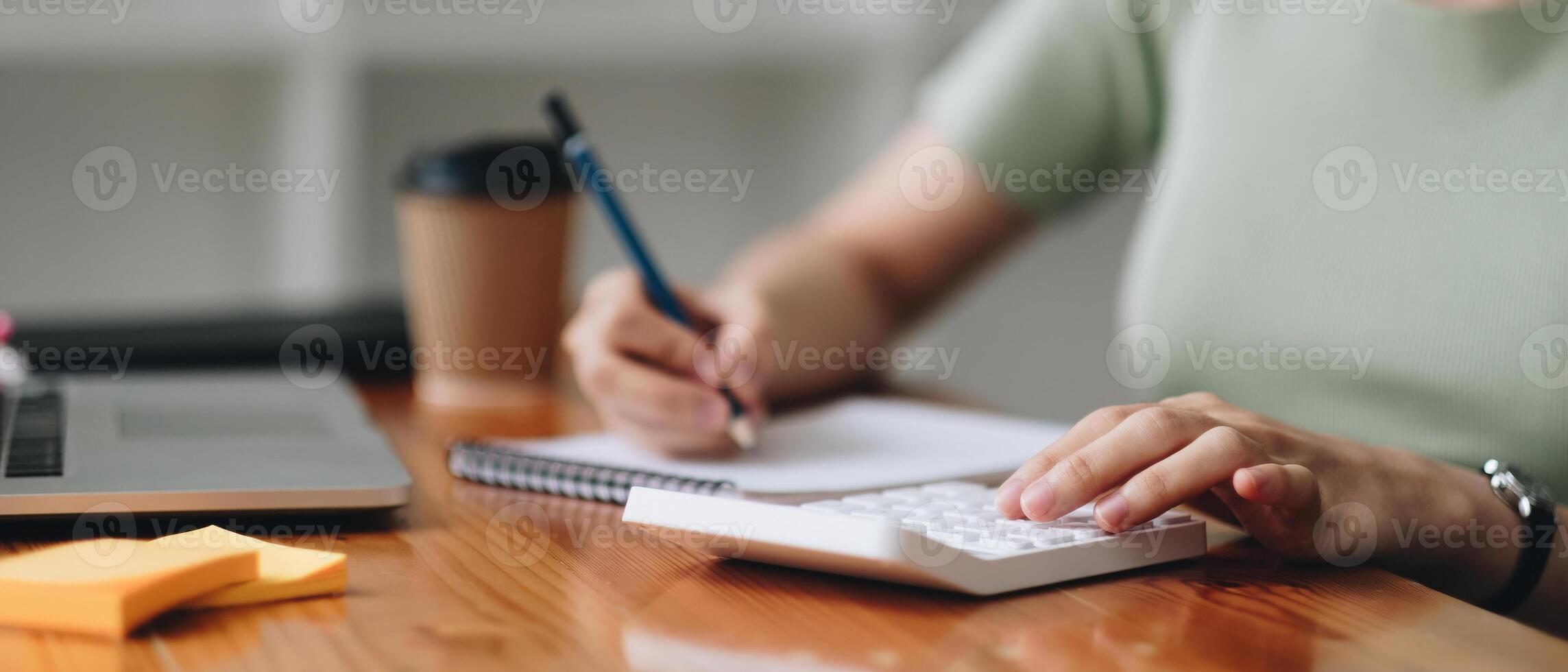 close-up shot of accountant using calculator while taking notes on office desk. photo