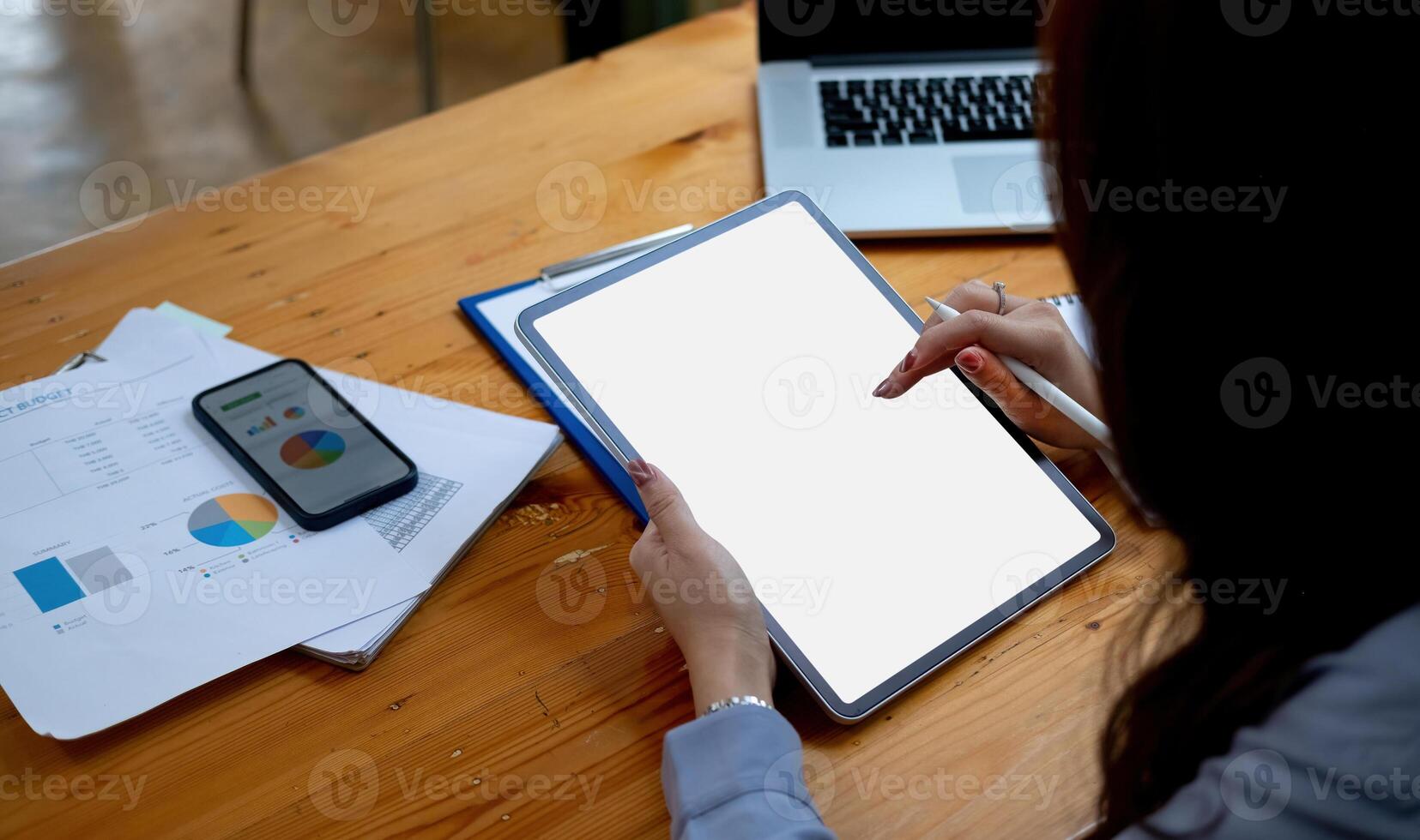 businesswoman holding a pen to use a tablet blank white screen in office working. Mock up. business financial concept photo