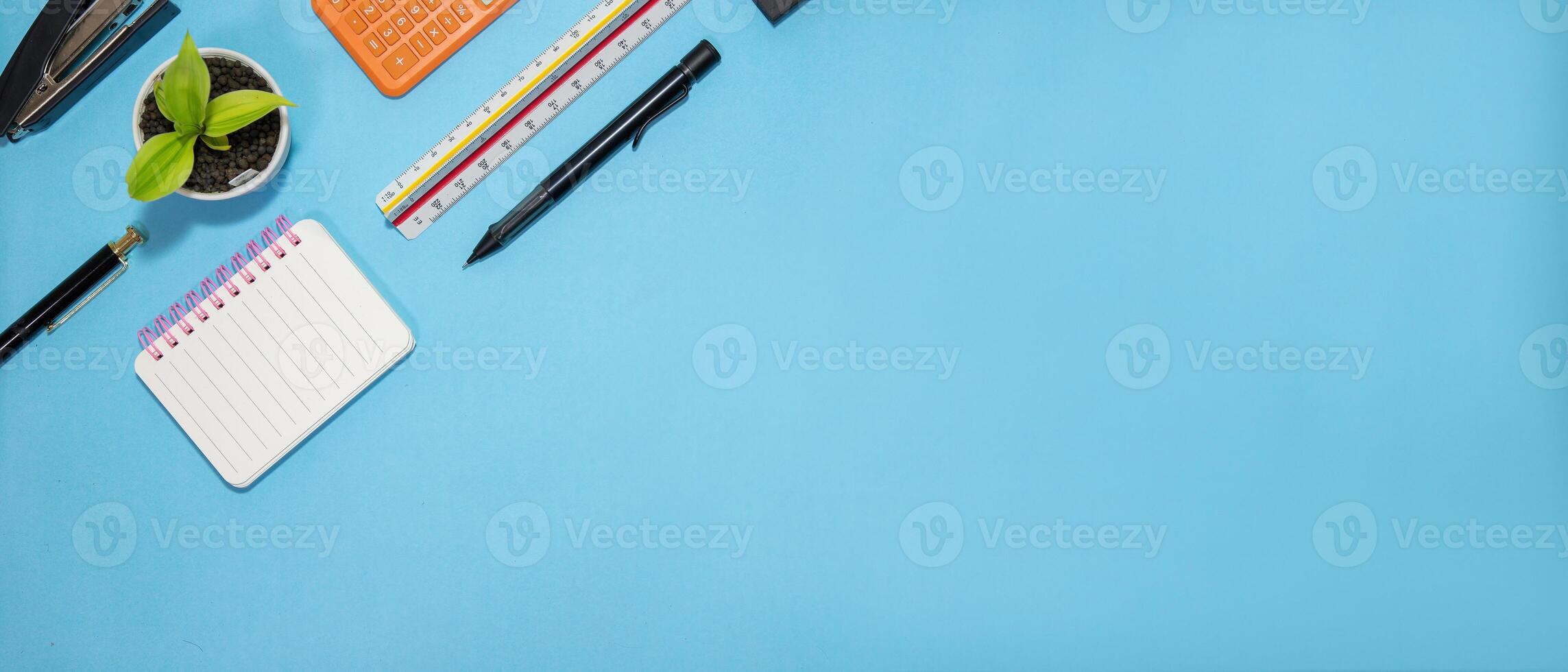 Education or back to school Concept. Top view of Colorful school supplies with books, color pencils, calculator, pen cutter clips and apple on blue pastel background. Flat lay photo