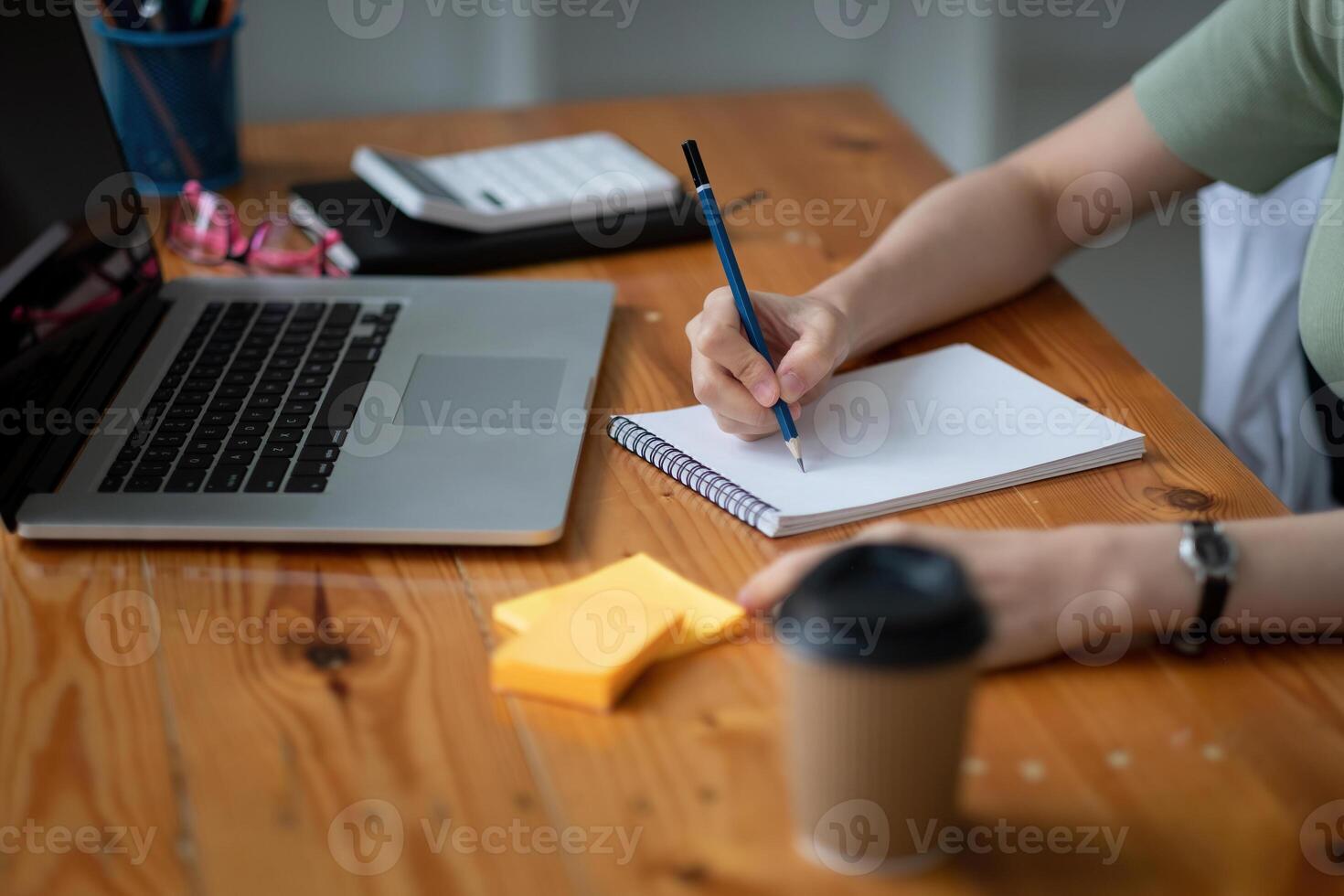 Cropped photo of woman writing making list taking notes in notepad working or learning on laptop indoors- educational course or training, seminar, education online concept