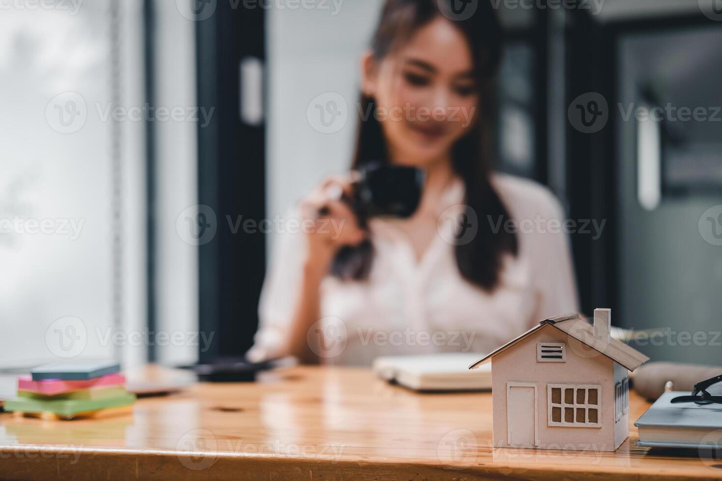 Real estate woman with house model on working desk for investment to buying property - selective focus at house model. photo