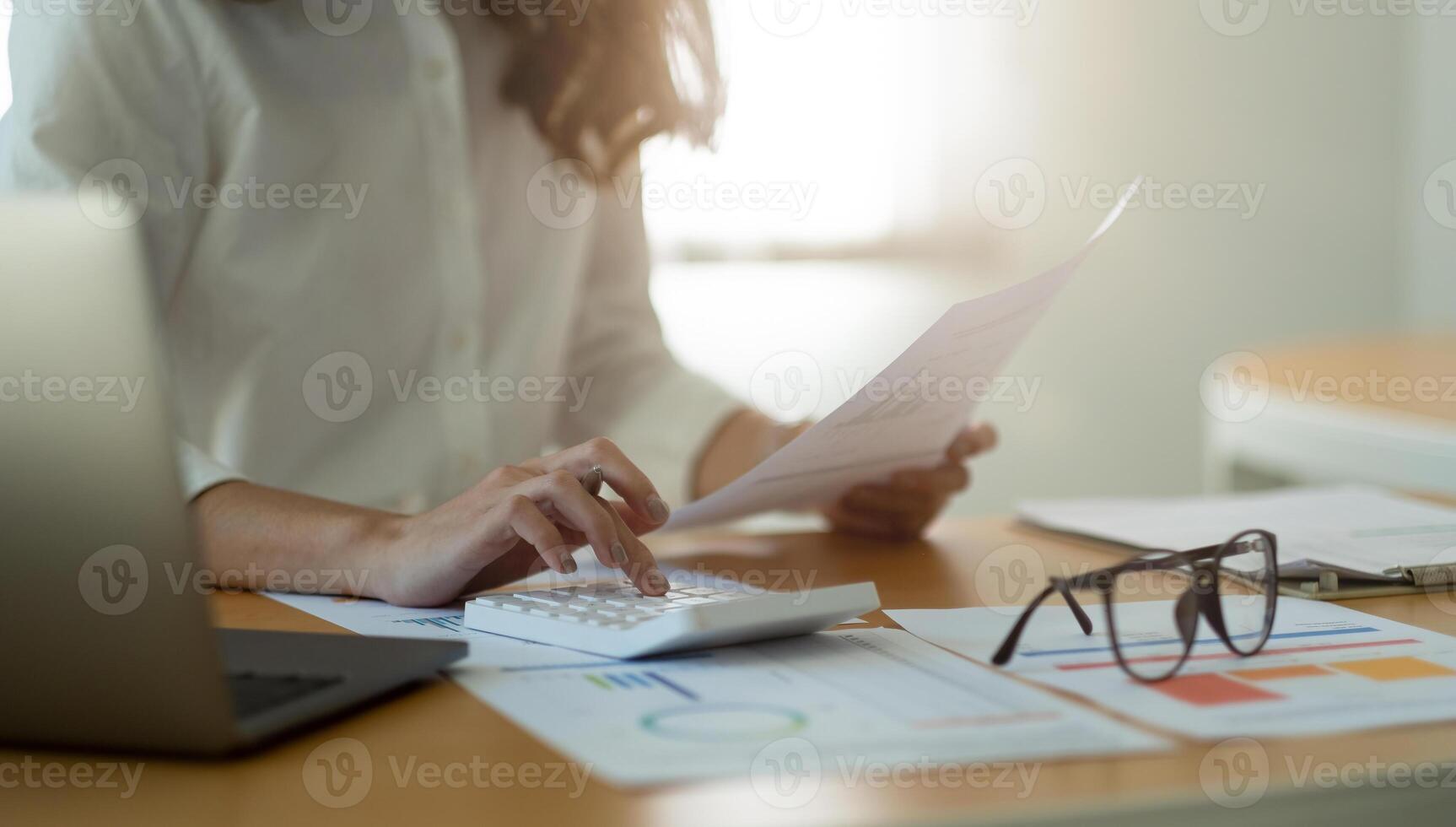 Businesswoman or accountant working Financial Manager Researching Process accounting calculate with calculator for analyse market graph data stock information review on the table in office. photo
