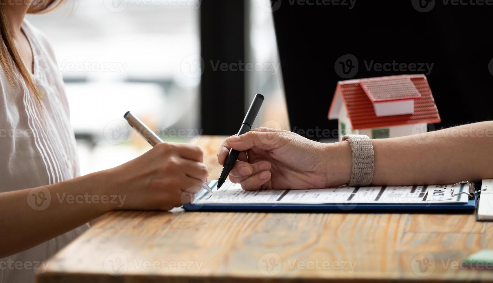 close up view hands of businessman signing leasing home documents and have a apartment keys on paperwork photo