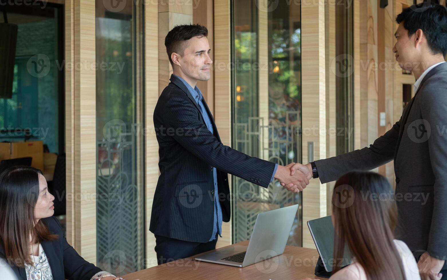 Group business people handshake at meeting table in office together with confident. Young businessman and businesswoman workers express agreement of investment deal photo