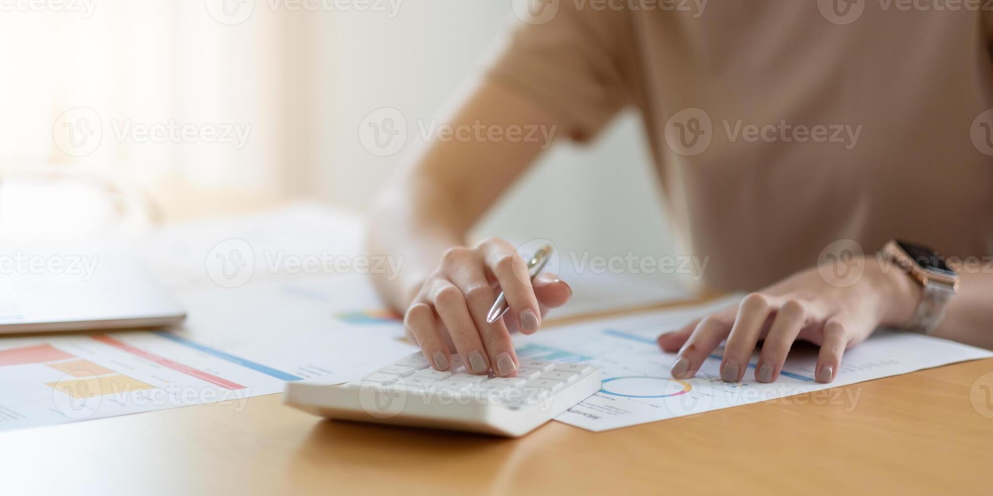 Close up woman using calculator and laptop, reading documents, young female checking finances, counting bills or taxes, online banking services photo