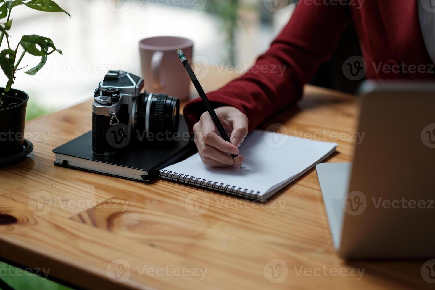 Close up hand of girl writing some data in notebook while studying online course on computer laptop, Learning without school or home education concept photo