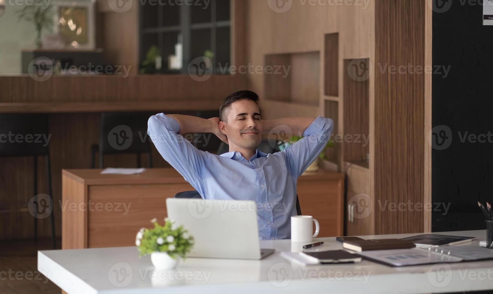 Relaxed calm caucasian businessman resting sit at office desk after working for financial with laptop computer. photo