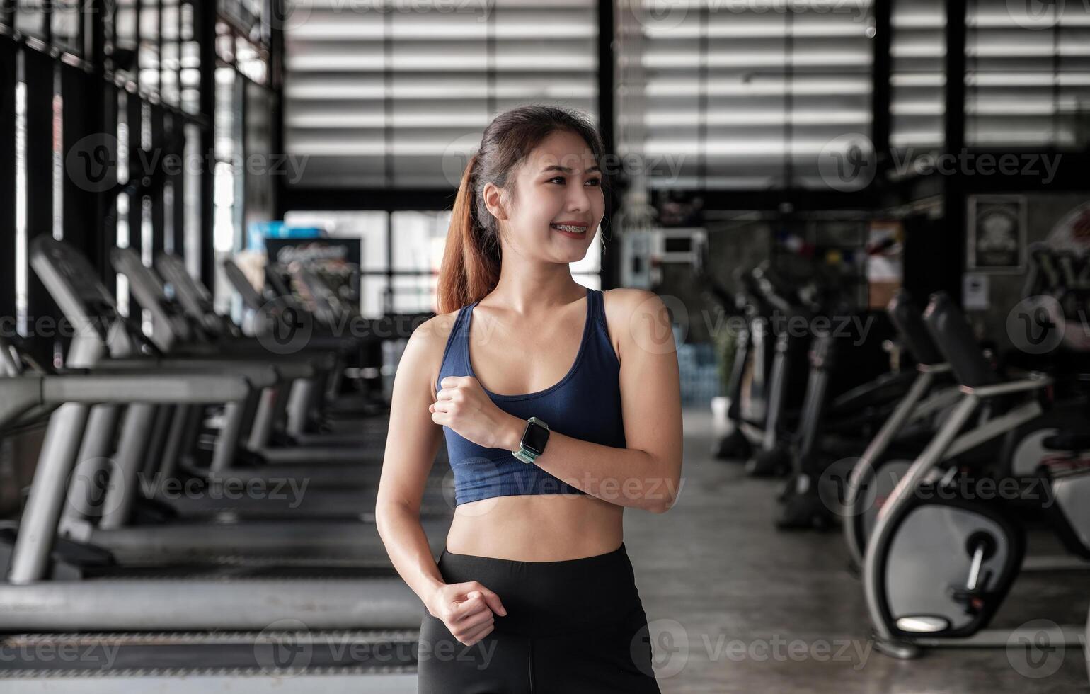 Portrait of confident beautiful asian fitness woman standing after exercise in gym. Concept of slim and healthy happy girl workout photo