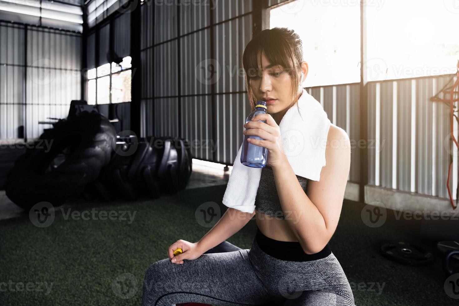 joven asiático atlético mujer Bebiendo agua después rutina de ejercicio o ejercicio en aptitud gimnasia. foto