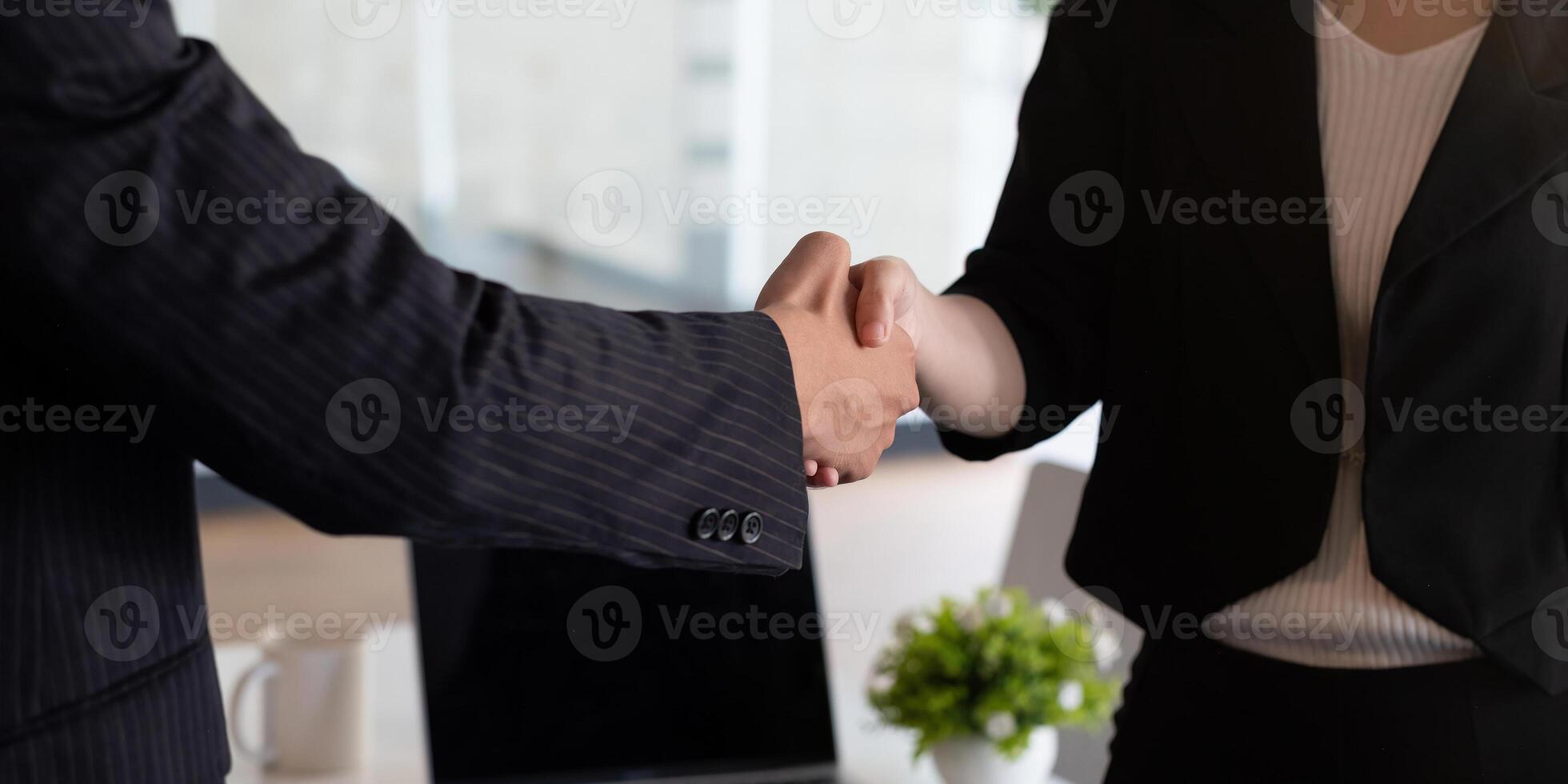 Business people handshake at meeting table in office together with confident . Young businessman and businesswoman workers express agreement of investment deal photo