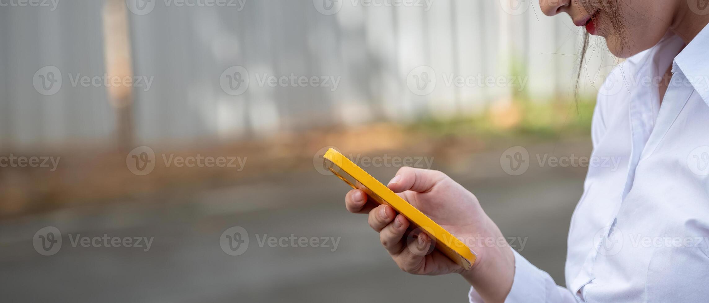 Close up photo of woman's hands touching the screen of a modern mobile phone while standing on a blurred street background. Hipster girl is typing e-mails on her smartphone using wi-fi connection