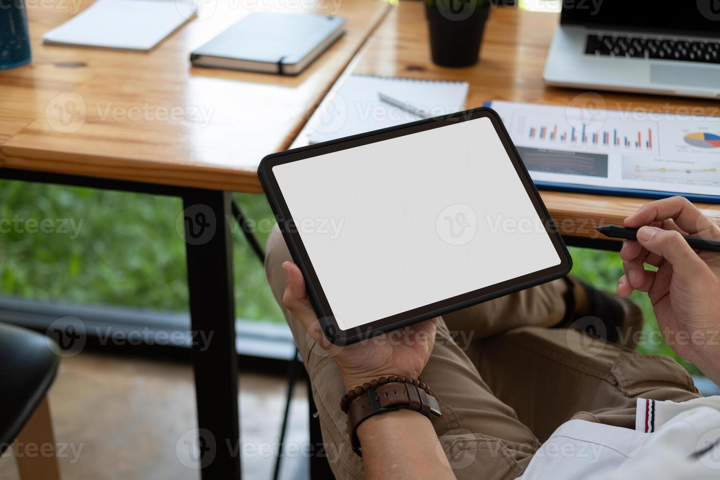 Cropped shot of a man sitting at modern office room and using blank white screen tablet, businessman using pen stylus photo