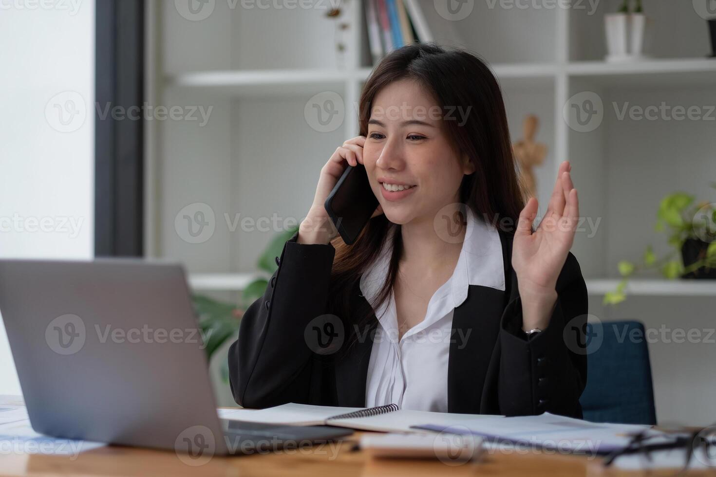 Young accountant business asian woman with smartphone to call marketing consultants and using laptop computer to analyze sales growth in the global workplace market. accounting concept. photo