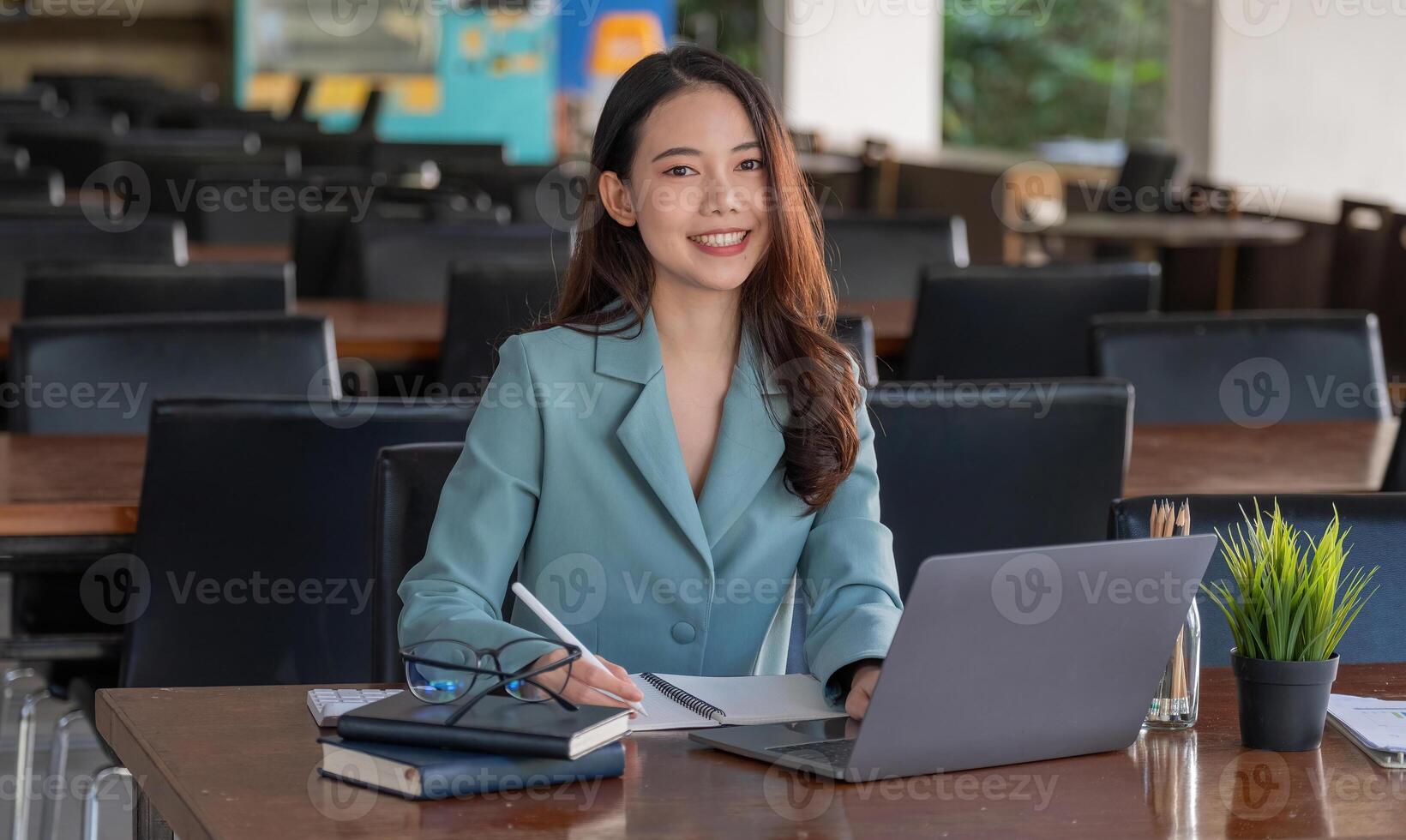 Portrait of Asian young female working on laptop during taking note at office. photo