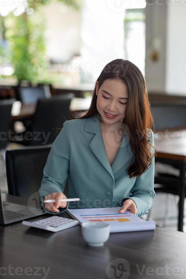Finances Saving Banking Concept, Asian woaman accountant calculations income and analyzing financial graph data with calculator photo