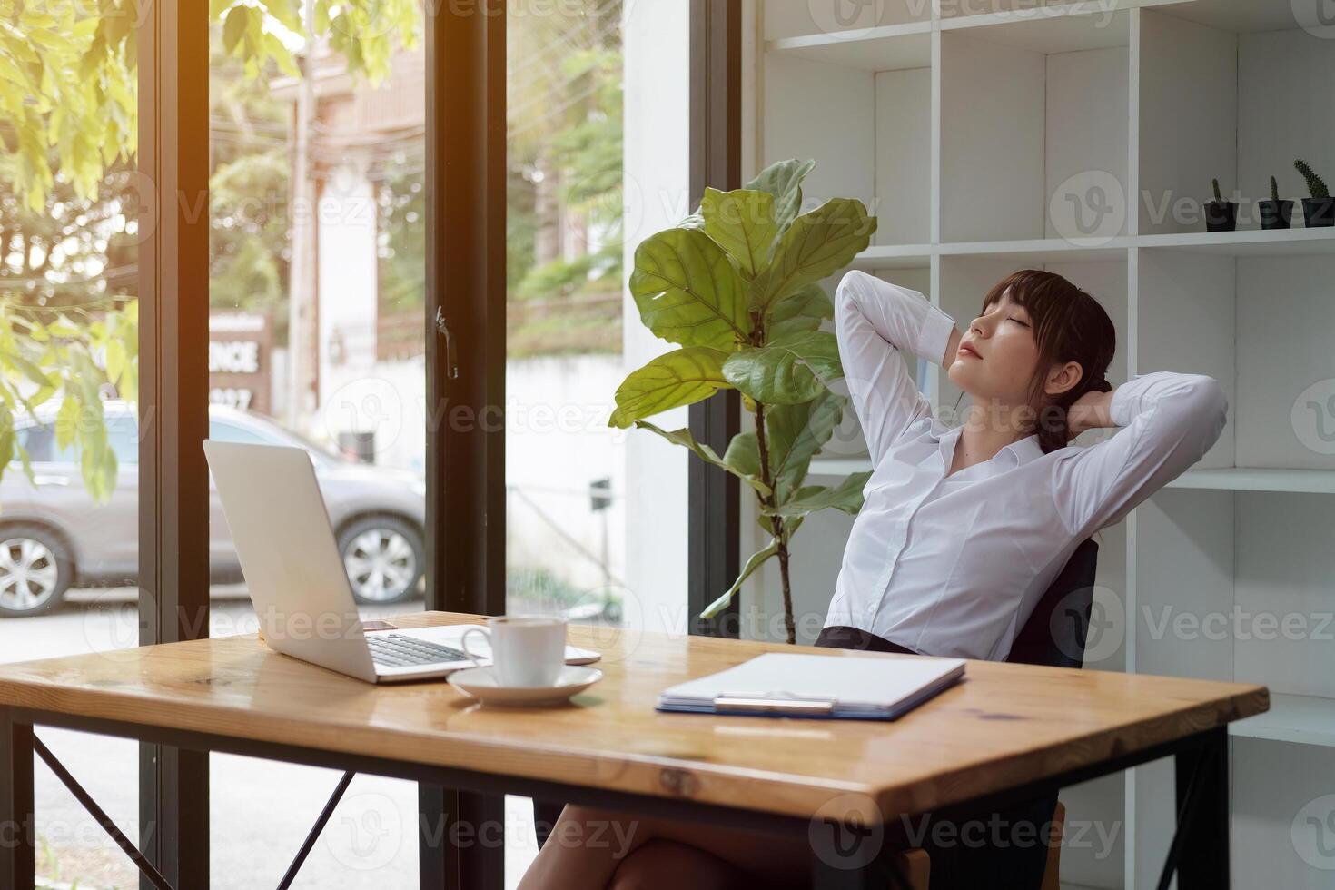 Young asian woman is stretching her shoulders during online meeting, webinar or online learning at home photo