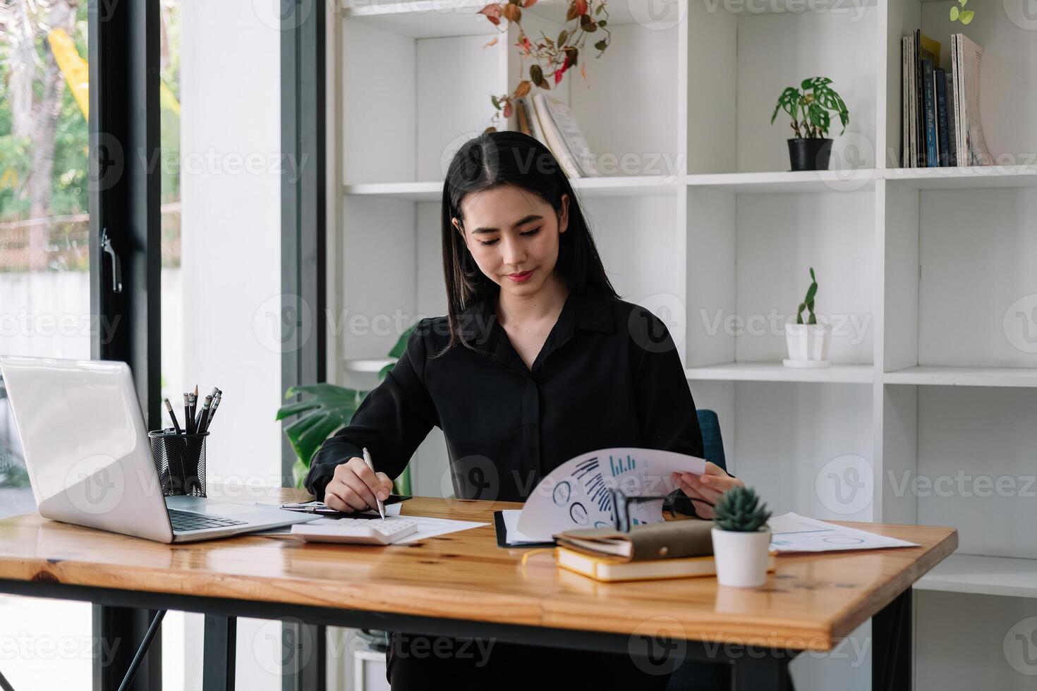 Portrait of Asian young female Businesswoman working on laptop computer doing finances,accounting analysis,report,data and pointing graph at the office photo