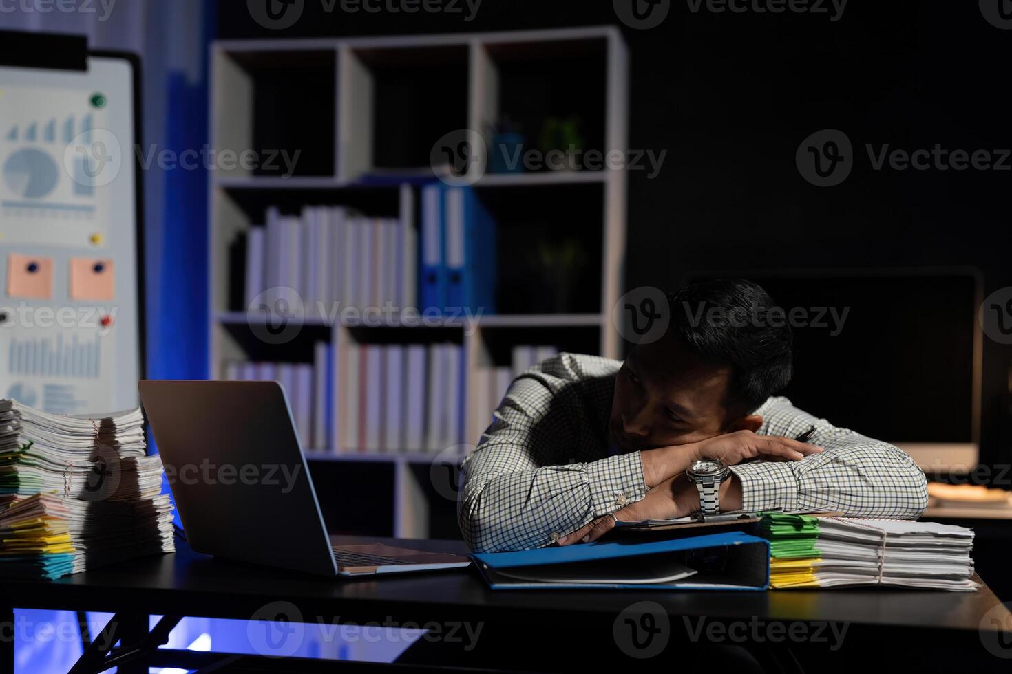 Exhausted businessman sleeping at his desk and working overtime late at night, he is surrounded by piles of paperwork photo
