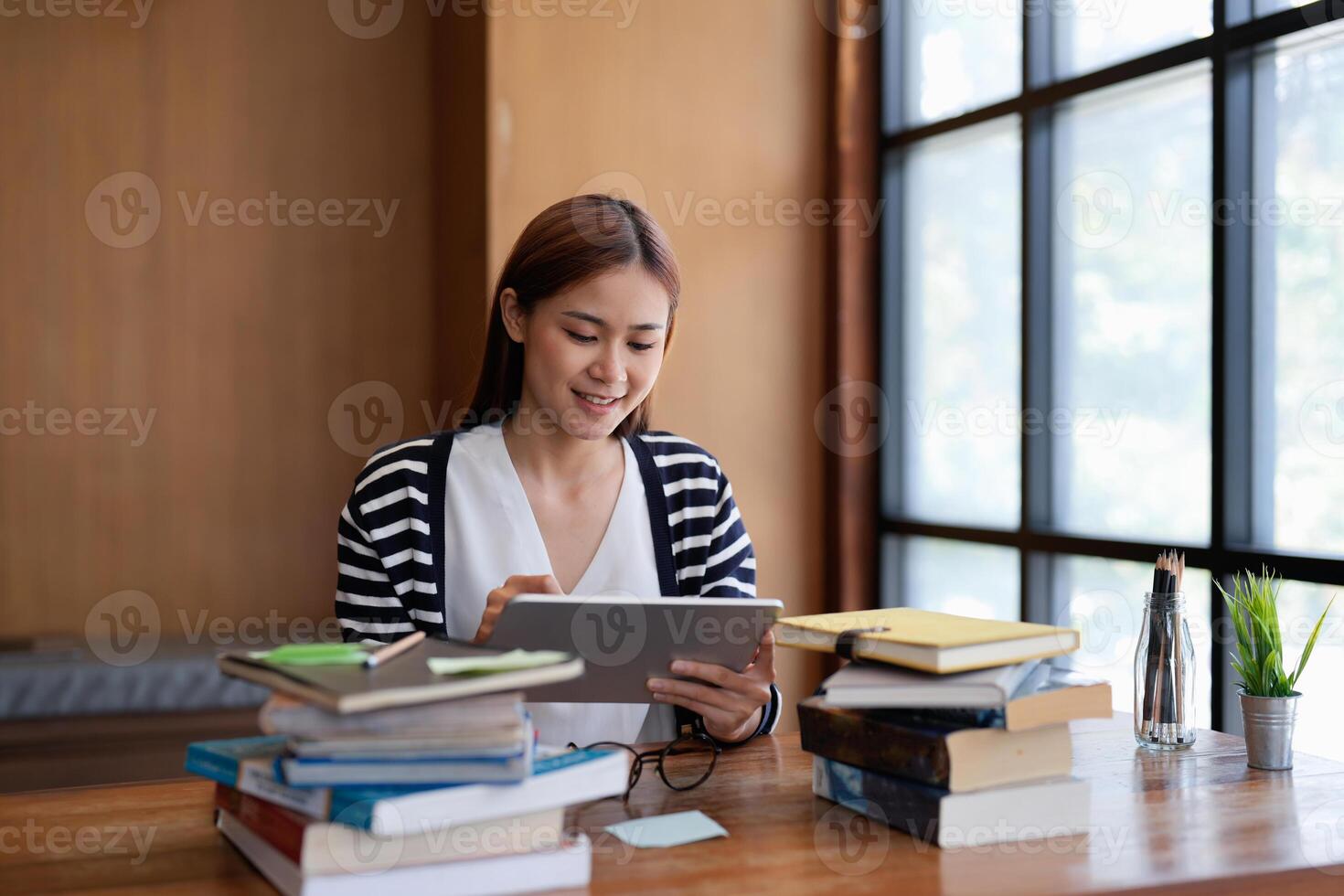 Young asian woman student working on digital tablet in library. photo