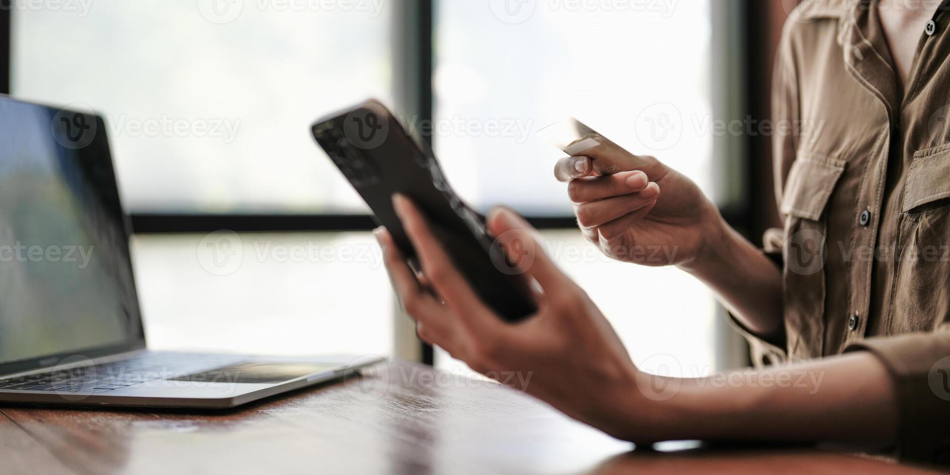 Close up female hands holding credit card and smartphone, young woman paying online, using banking service, entering information, shopping, ordering in internet store, doing secure payment photo
