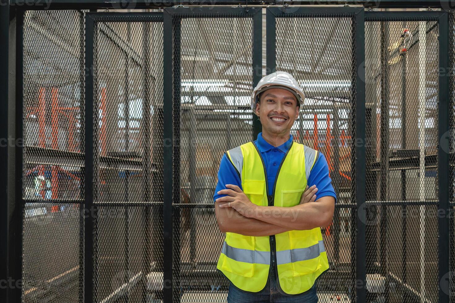 Smiling portrait of a male supervisor standing in warehouse with his arm crossed looking at camera photo