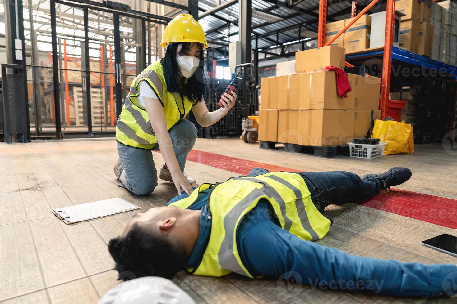 A female warehouse worker using a walkie-talkie called the factory's first aid team to rescue an unconscious man. pass out or blackout, unsafe, emergency photo